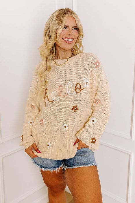A model with long blonde hair showcasing a stylish sweater.