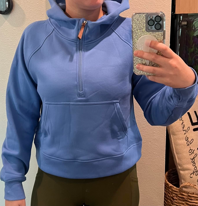 A reviewer wearing a hoodie and holding a phone with one hand, face not visible.