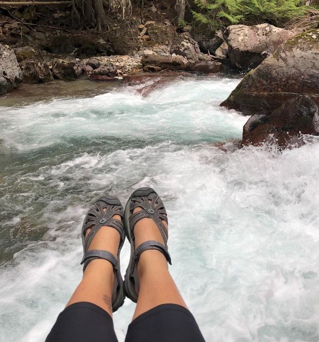 reviewer hiking near a waterfall while wearing the sandals