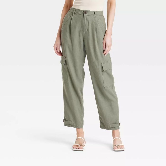A person wearing high-waisted cargo pants with functional pockets and a sleeveless top, standing in open-toe sandals.
