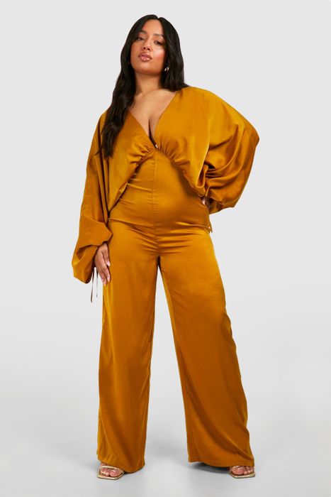 A model poses in a fashionable, loose-fitting mustard-yellow jumpsuit with wide legs and long sleeves.