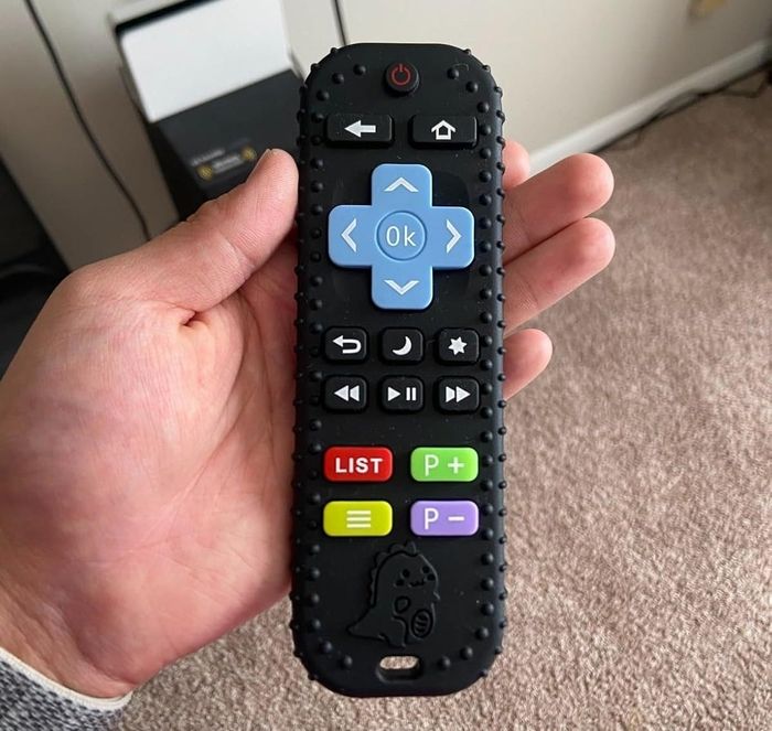 A person holding a TV remote with a textured grip and large, colorful buttons, designed for ease of use.