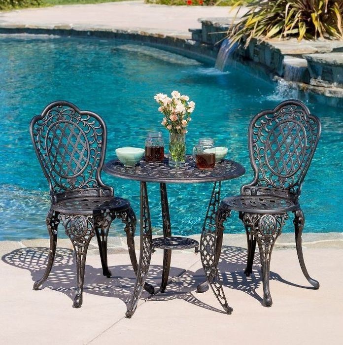 The chic table and chair set placed beside a pool, creating a serene and stylish outdoor setting.
