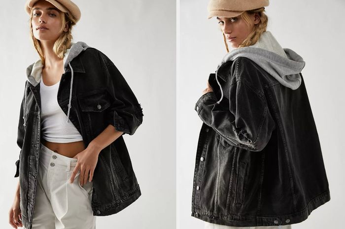 Model sporting an oversized black denim jacket, left unbuttoned with a cozy gray hood attached, showing the back view of the jacket styled with white pants and a tan hat.