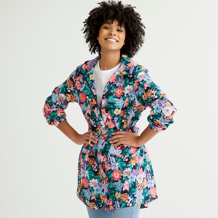 A model is seen wearing a floral packable raincoat in a blend of red, blue, and green hues.