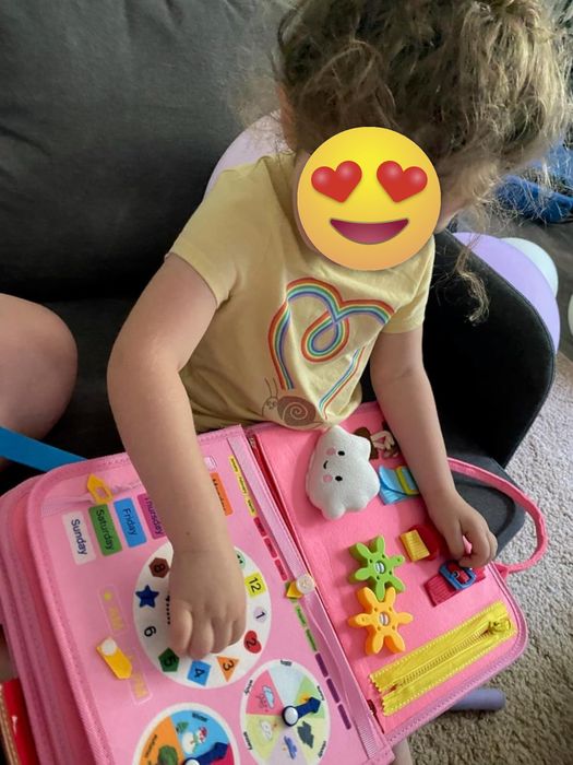 A child is enjoying an educational activity book featuring shapes, numbers, and a toy cloud.