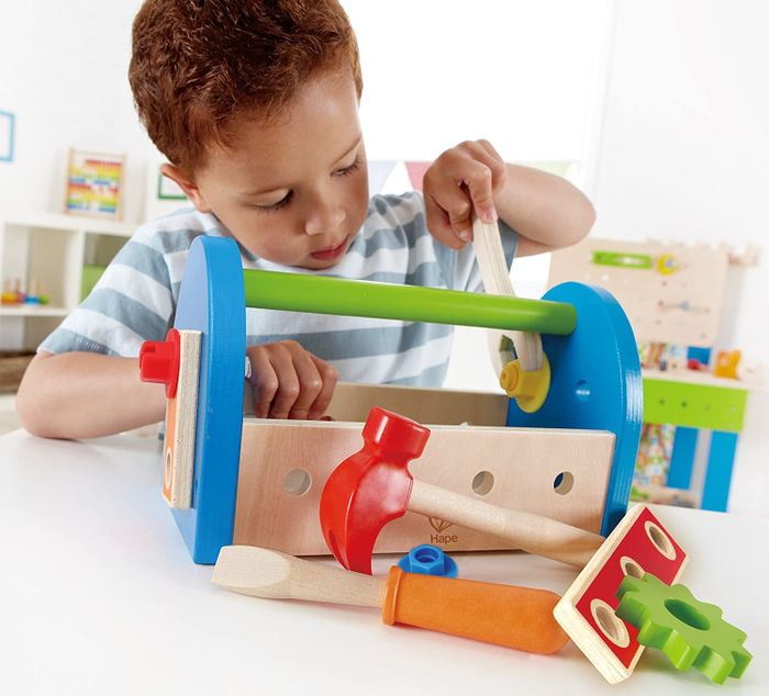 A child model playing with a vibrant wooden tool kit