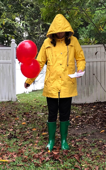 A reviewer is seen wearing a yellow rain jacket with the hood pulled up, showcasing its practicality and style.