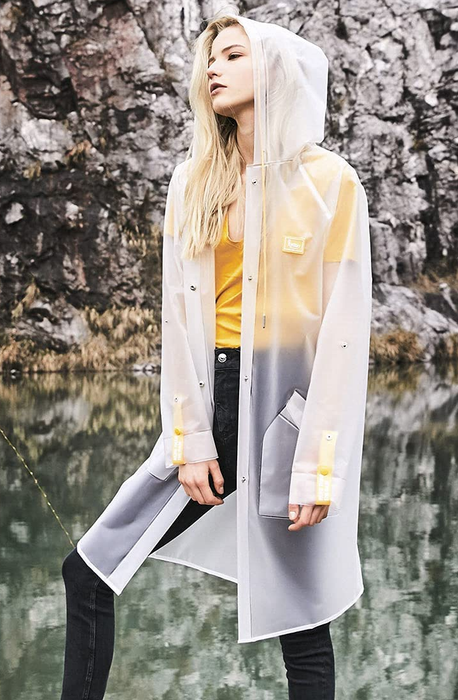 A model wearing the clear raincoat with yellow buttons and straps.