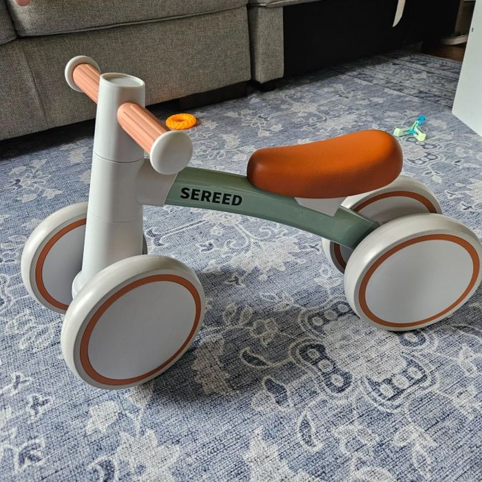 A toddler's balance bike with the 'Sereed' brand label on the frame, sitting on a carpeted floor.