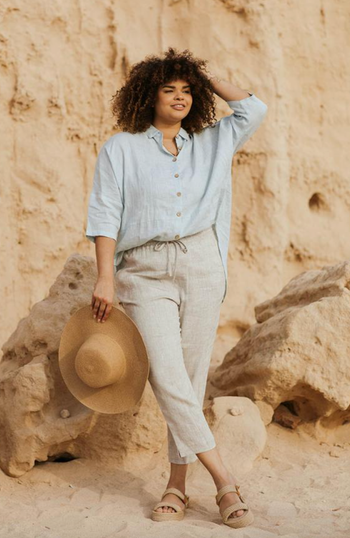 Model wearing beige linen pants, standing in front of a rock formation