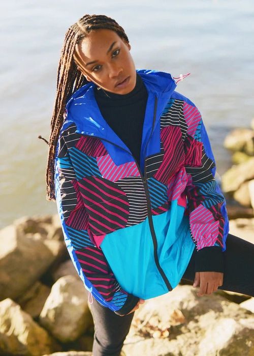 The model is dressed in a hooded windbreaker featuring a bold blue and pink Akira print.
