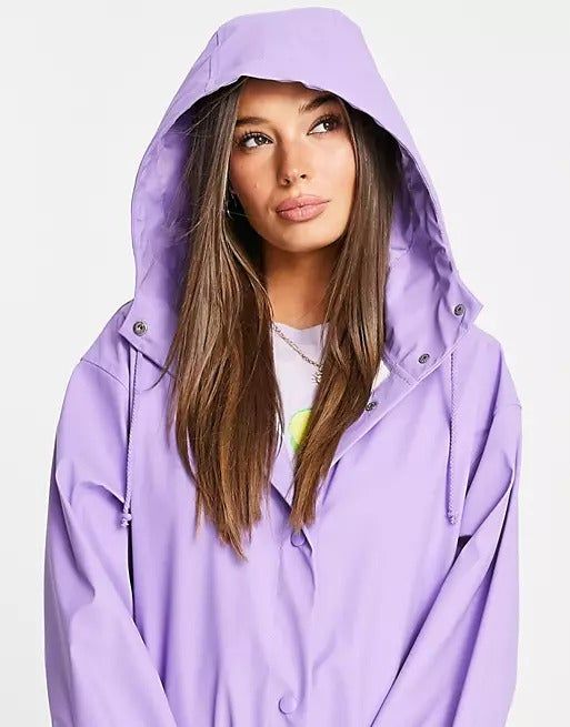 A model dons a lavender raincoat with the hood up, adding an extra layer of protection against the rain.