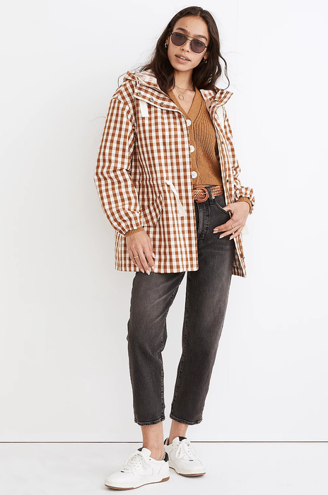 A model showcases a brown gingham raincoat left unzipped for a more relaxed look.