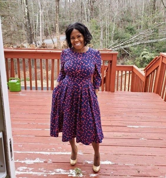 Reviewer in a dress featuring a blue and purple floral print.
