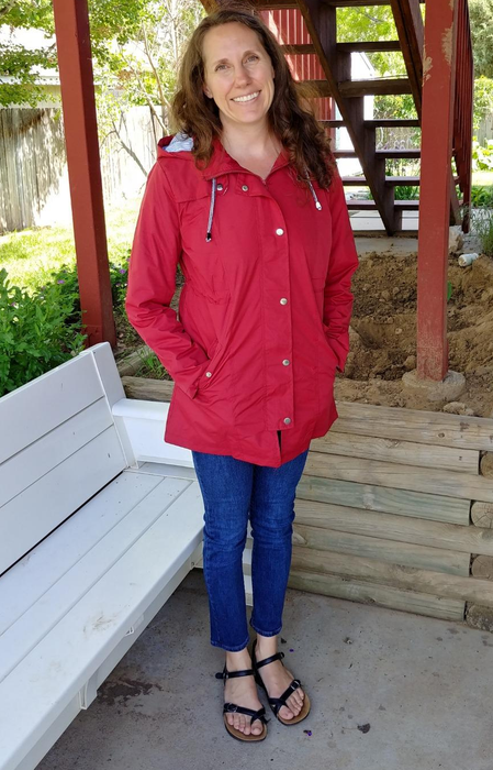 A reviewer models a bold red rain jacket, perfect for adding a pop of color on a rainy day.