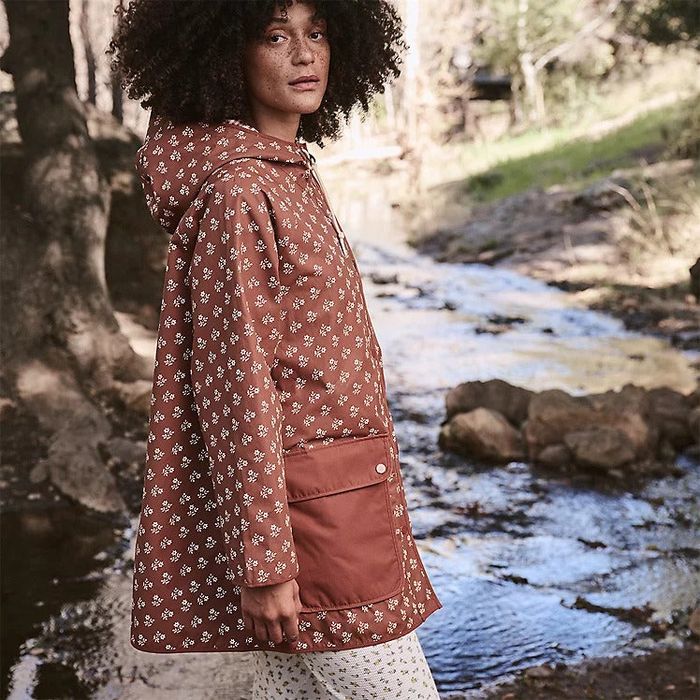 A model dressed in a brown floral rain jacket, featuring large pockets.