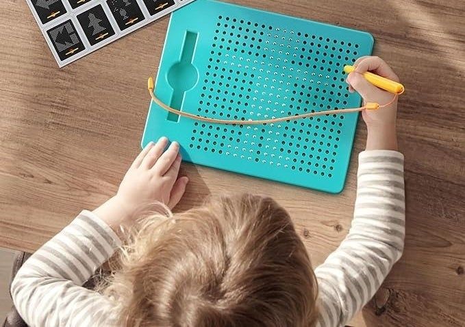 A child using a magnetic board with example ideas laid out on a table