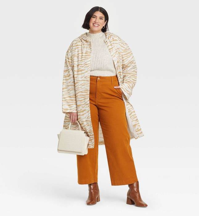 A model sports a beige-colored zebra print raincoat that reaches down to their knees, making a bold statement in the rain.