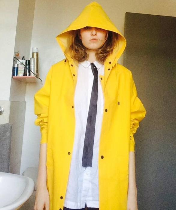 A reviewer models the vibrant yellow trench raincoat, showcasing its stylish yet practical design.