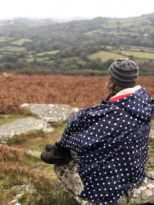 Another reviewer showcasing the blue polka dot poncho jacket on a hiking trip.