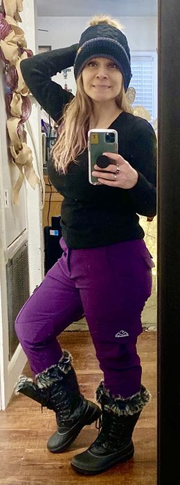 Reviewer posing for a mirror selfie in purple snow pants