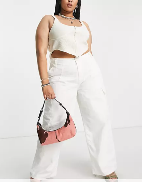model rocking white cargo pants, carrying a tiny cowprint bag