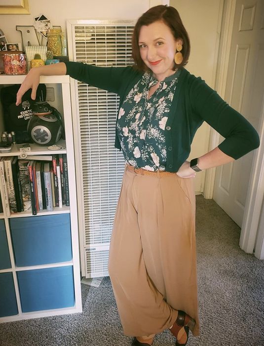 A reviewer is wearing flowing tan palazzo pants, styled with a blouse and cardigan.