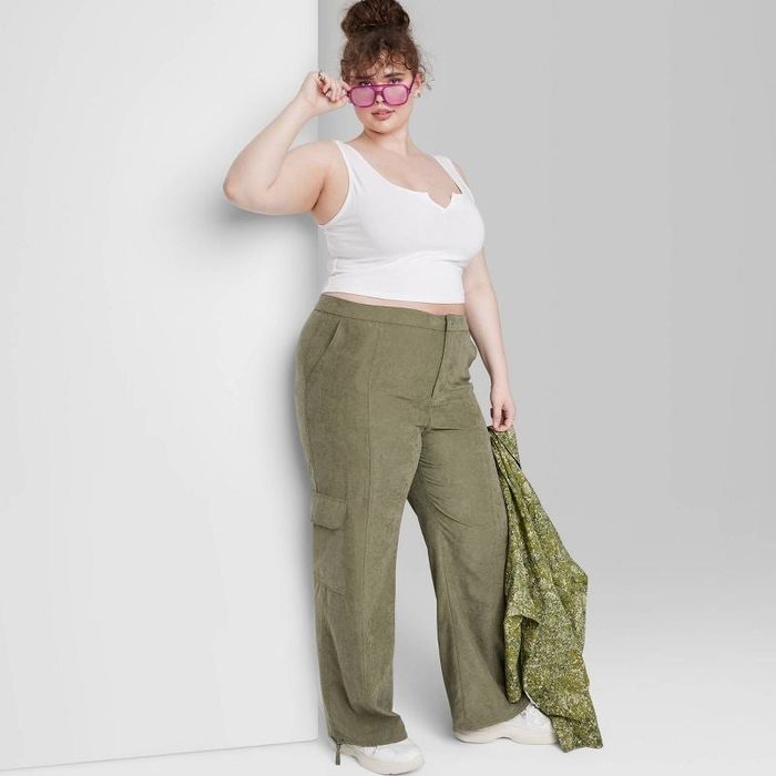 A model is styled in olive green cargo pants, blending comfort with a trendy edge.
