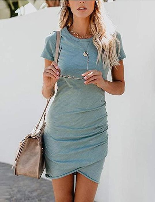 The model is wearing a t-shirt dress accessorized with necklaces and a shoulder bag.