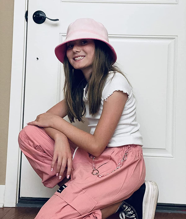 Reviewer, a teen kneeling in pink cargo pants with a chain and a bucket hat