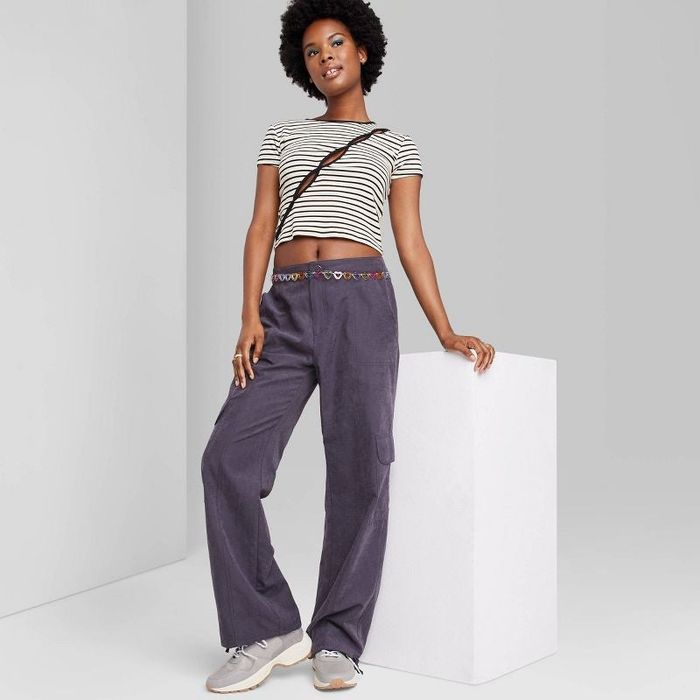 A model is wearing purple cargo pants paired with a belly chain for an added flair.