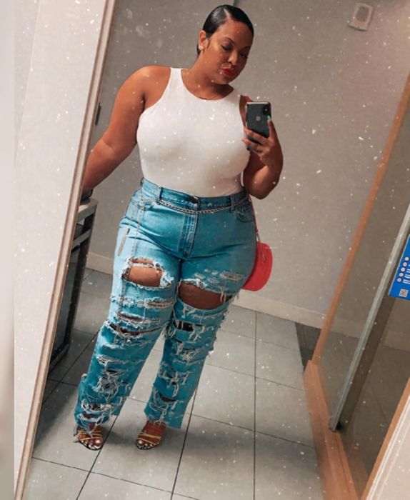 A reviewer styling a white bodysuit with ripped jeans and heels for a chic look.