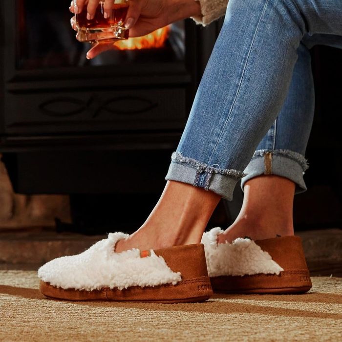 A model wears the cream-colored version of the slippers for a soft and cozy look.
