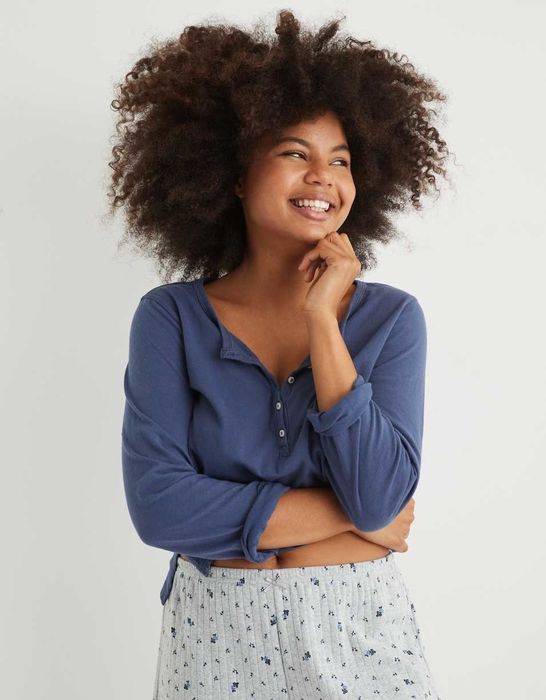 The model is dressed in a dark blue long-sleeve henley T-shirt paired with gray pajama pants.