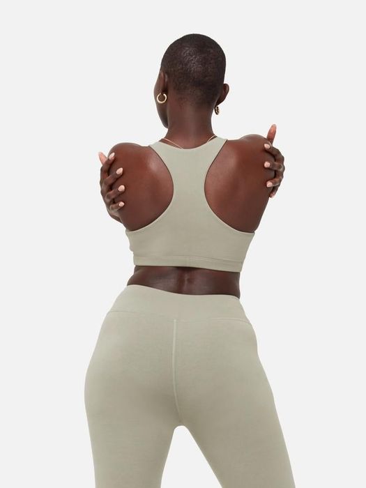 Model showing off the sage green version of the racerback sports bra, also paired with matching leggings for a sleek look.