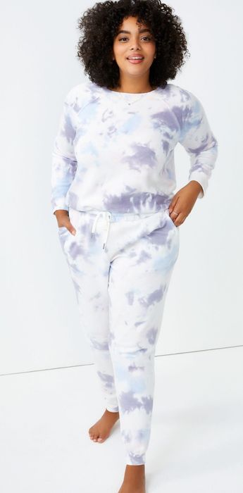 A model wears white, purple, and blue tie-dye joggers, paired with a matching sweatshirt for a coordinated look.