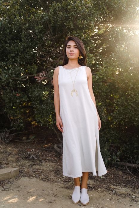 A model showcasing the light gray version of the dress, paired with white slip-on mules and gold jewelry for a chic touch.