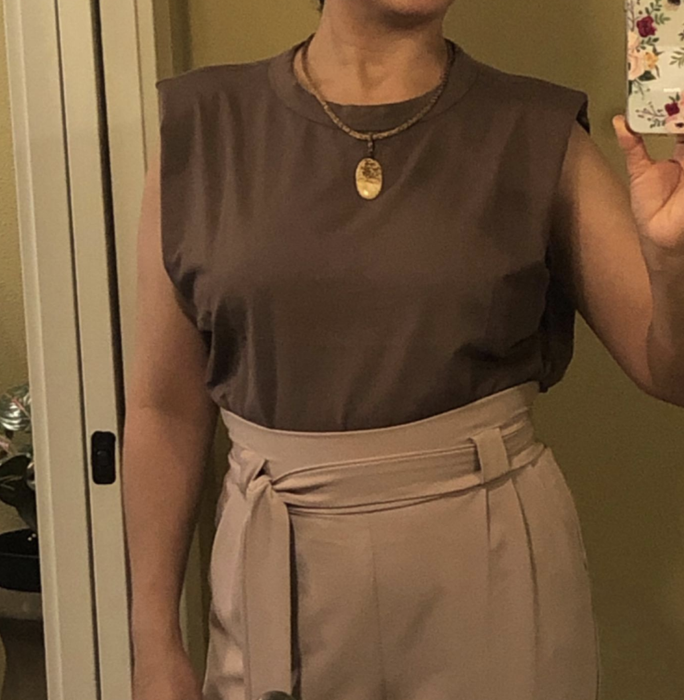 A customer is wearing the sleeveless blouse in khaki.