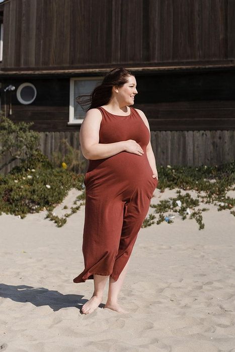 A pregnant model showcases the rust-colored column dress.
