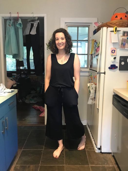 The reviewer is wearing a black sleeveless terry-cloth jumpsuit while walking through their kitchen.