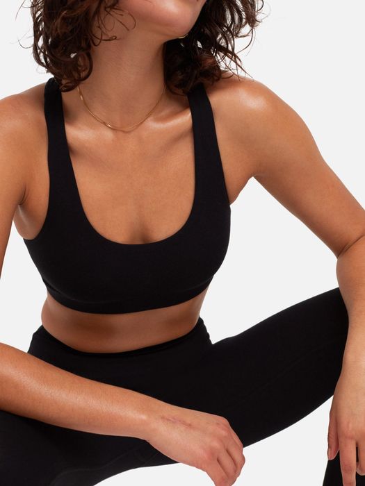 Model sporting the black version of the racerback sports bra, paired with matching leggings.
