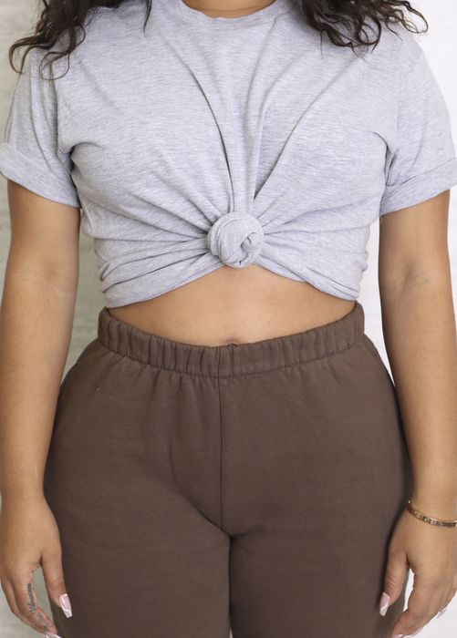 A model is wearing a gray t-shirt with a knot at the front.