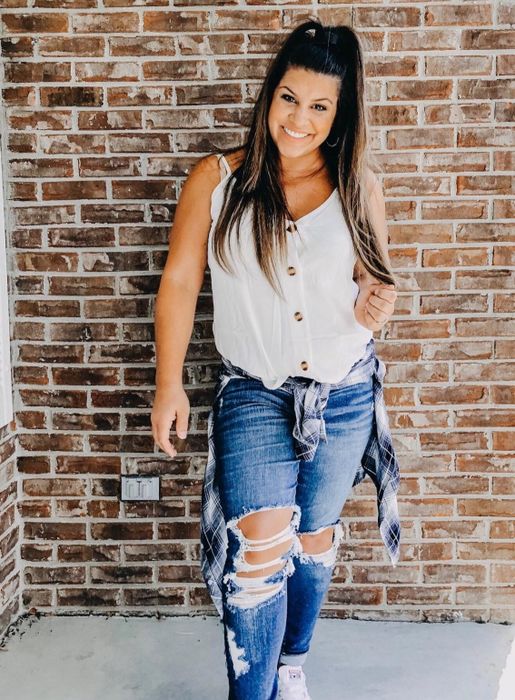 A reviewer is seen wearing the white tank top with a pair of ripped jeans.