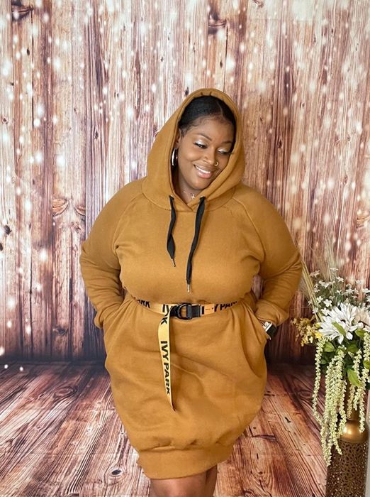A reviewer rocks a mustard yellow hoodie dress paired with an Ivy Park belt while unwinding at home.