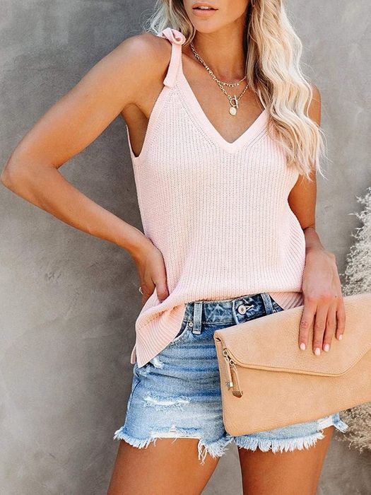 A model is wearing a pink top paired with denim shorts.