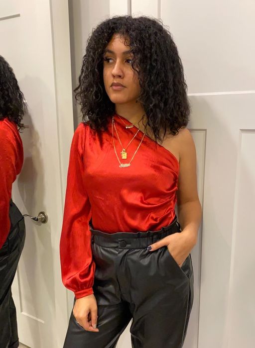 A reviewer rocking the red one-sleeve bodysuit, tucked neatly into pants.