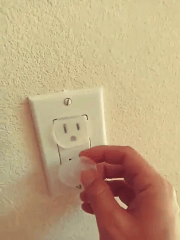 A person installs the outlet cover into a wall socket
