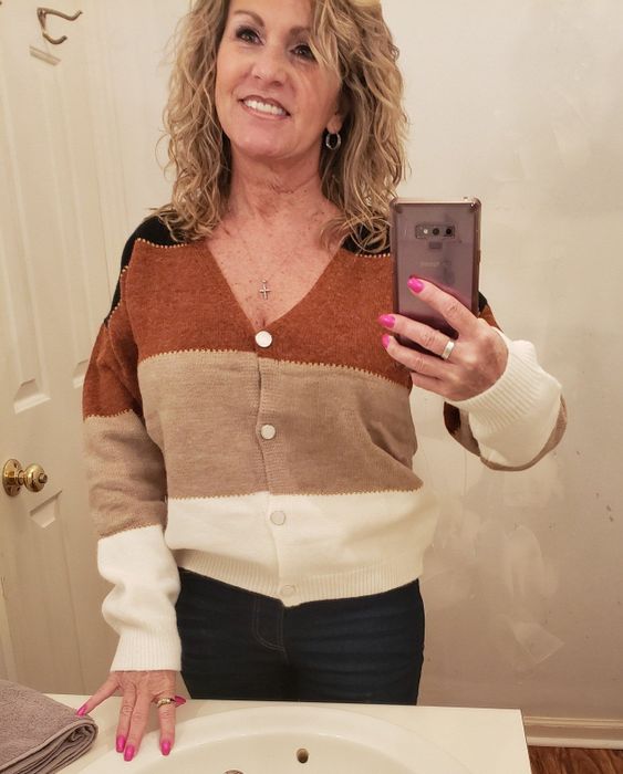 A reviewer is seen wearing the sweater featuring horizontal stripes in brown, black, tan, and white.
