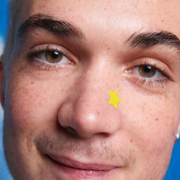 A yellow star-shaped pimple patch on a model's nose